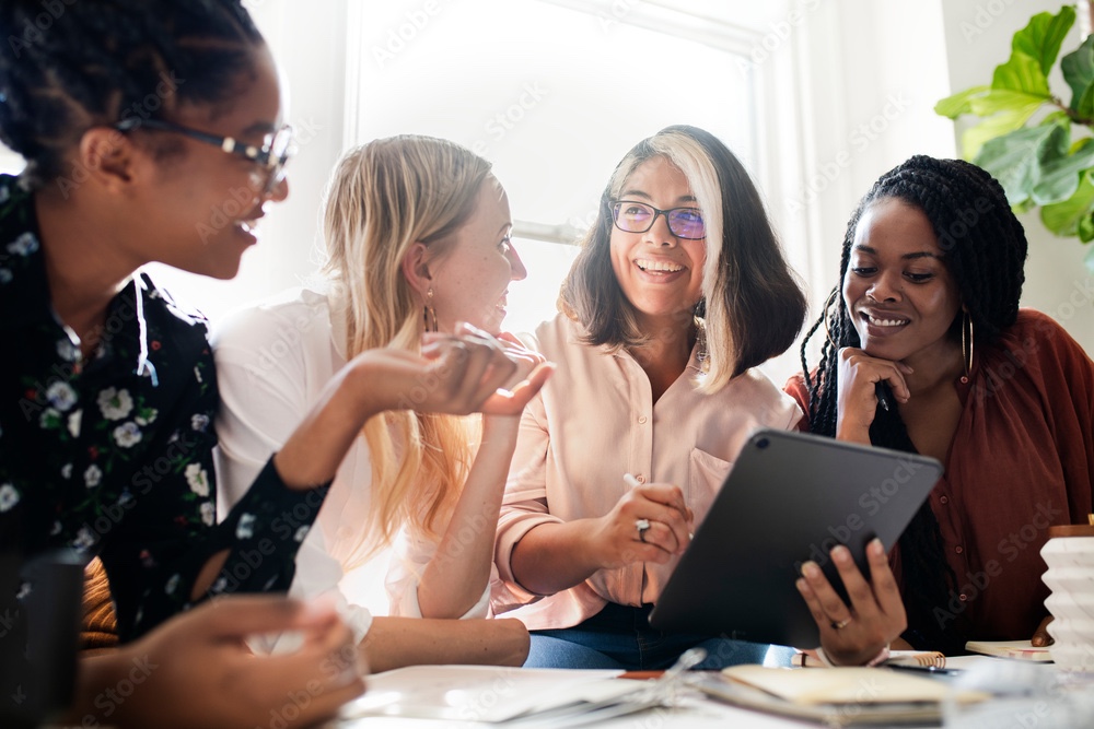 Diverse businesswomen including African American professionals collaborating and smiling while working together